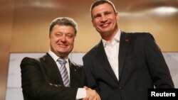 Ukrainian businessman, politician and presidential candidate Petro Poroshenko (L) and heavyweight boxing champion and Ukrainian Democratic Alliance for Reform party leader Vitali Klitschko shake hands during a rally at Poroshenko's election headquarters i