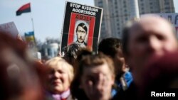 People hold a sign depicting Russian President Vladimir Putin as Adolf Hitler as they attend a unity rally at Independence Square, in Kyiv, Ukraine, March 23, 2014.