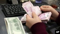 FILE - In this file photo, a woman counts U.S. dollar and Turkish lira banknotes at a currency exchange office in Istanbul, Turkey.