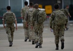 Members of the British armed forces walk to the air terminal after disembarking a RAF Voyager aircraft at Brize Norton, England, as they return from helping to evacuate people from Kabul airport in Afghanistan, Aug. 28, 2021.