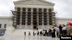 FILE - Visitors to the Supreme Court are pictured in the rain in Washington.