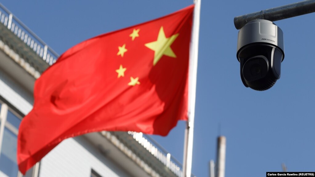 A security camera overlooking a street is pictured next to a nearby flag of China in Beijing, China on November 25, 2021. (REUTERS/Carlos Garcia Rawlins)