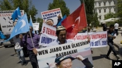 Uighurs living in Turkey hold a poster of Chinese PM Wen Jiabo with a banner that reads ' the premier of the country of blood' as they march to the Chinese embassy in Ankara, Turkey, to commemorate the second anniversary of deadly ethnic unrest in China'