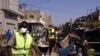 Des employés municipaux portant des masques à titre préventif contre le coronavirus COVID-19 nettoient les étals autour du marché Tilene à Dakar le 22 mars 2020 suite à la décision du maire de nettoyer les étals et de fermer les marchés tous les soirs à p
