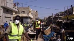 Des employés municipaux portant des masques à titre préventif contre le coronavirus COVID-19 nettoient les étals autour du marché Tilene à Dakar le 22 mars 2020 suite à la décision du maire de nettoyer les étals et de fermer les marchés tous les soirs à p