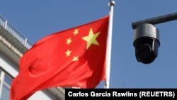 Kamera keamanan di samping bendera yang sedang berkibar di Beijing, China pada 25 November 2021. (Foto: REUTERS/Carlos Garcia Rawlins)