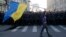 A man with a Ukrainian flag walks past riot police standing guard during an anti-war rally in Moscow, Sept. 21, 2014. 