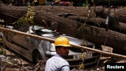 An electricity department worker rests next to uprooted trees after Tuesday night's dust storm in New Delhi, India, May 16, 2018. 