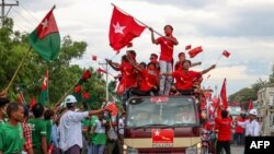 Supporters of the National League for Democracy (NLD) party on a motorcade pass supporters of the opposition Union Solidarity and Development Party (USDP), seen at left, during a campaign in Wundwin, near Mandalay on September 19, 2020. (Photo by Kyaw The