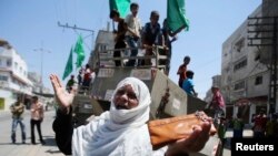 一位巴勒斯坦妇女站在以色列军事装备前面做手势。