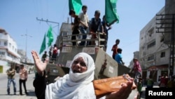 一位巴勒斯坦妇女站在以色列军事装备前面做手势。
