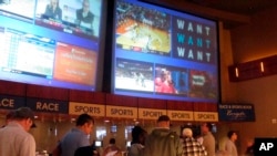 FILE - Gamblers line up to place bets on the NCAA men's college basketball tournament at the Borgata casino in Atlantic City N.J., March 21, 2019. 