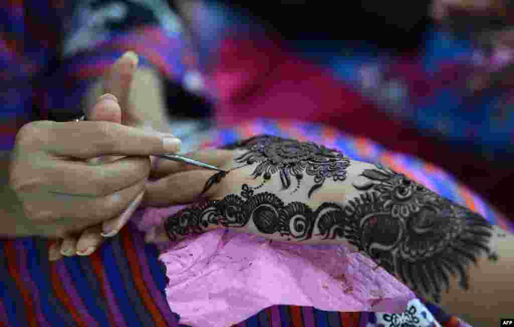 A Pakistani beautician applies a traditional henna design to the hand of a customer ahead of the Muslim festivities of Eid al-Fitr, in Karachi.