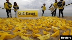 Des bénévoles de Amnesty International ont installé des bateaux en papier avec le slogan "SOS Europe" sur les plages espagnoles de San Sebastian à Barcelona, 22 avril 2015. 