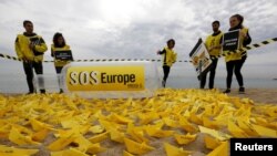 Voluntarios de Amnistía Internacional colocan botes de papel con el letrero "SOS Europa" en una playa de San Sebastián, en el norte de España.