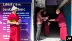 A bank employee standing in front of an ATM sprays sanitizer on a Tibetan Buddhist monk's palms to prevent the spread of coronavirus infection in Dharmsala, India, Monday, April 20, 2020. India recorded its biggest single-day spike in coronavirus…