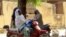 FILE - Women chatting while sitting on their bikes in a district of Maroua, northern Cameroon.