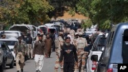 Pakistani paramilitary soldiers and police commandos gather outside the Afghan consulate following a shooting incident, in Karachi, Pakistan, Monday, Feb. 6, 2017. 