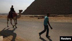 A man pulls a camel carrying a lone tourist at the Pyramids of Giza near Cairo October 19, 2011.