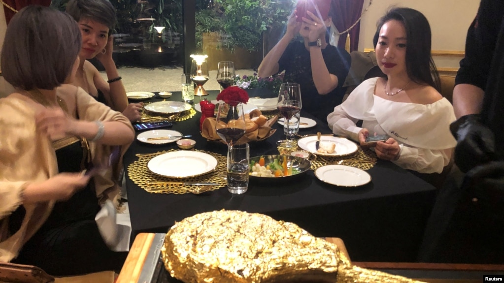 A customer takes pictures of a gold leaf-coated steak, tapping in on a wave of publicity after a government minister was caught on camera being fed the dish at a London restaurant, at a Dolce By Wyndham Hanoi Golden Lake hotel, in Hanoi, Vietnam December 7, 2021. (REUTERS)