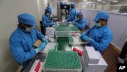 FILE - Employees pack boxes containing vials of Covishield, a version of the AstraZeneca vaccine at the Serum Institute of India in Pune, India, Jan. 21, 2021.