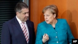 FILE - German Chancellor Angela Merkel, right, and German Foreign Minister Sigmar Gabriel, left, arrive for the weekly cabinet meeting at the Chancellery in Berlin, April 12, 2017.