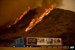 Flames from the Thomas fire burn above a truck on Highway 101 north of Ventura, California, Dec. 6, 2017.