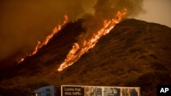 Flames from the Thomas fire burn above a truck on Highway 101 north of Ventura, California, Dec. 6, 2017.