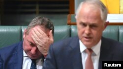 Australian Deputy Prime Minister Barnaby Joyce reacts as he sits behind Australian Prime Minister Malcolm Turnbull in the House of Representatives at Parliament House in Canberra, Australia, Oct. 24, 2017.