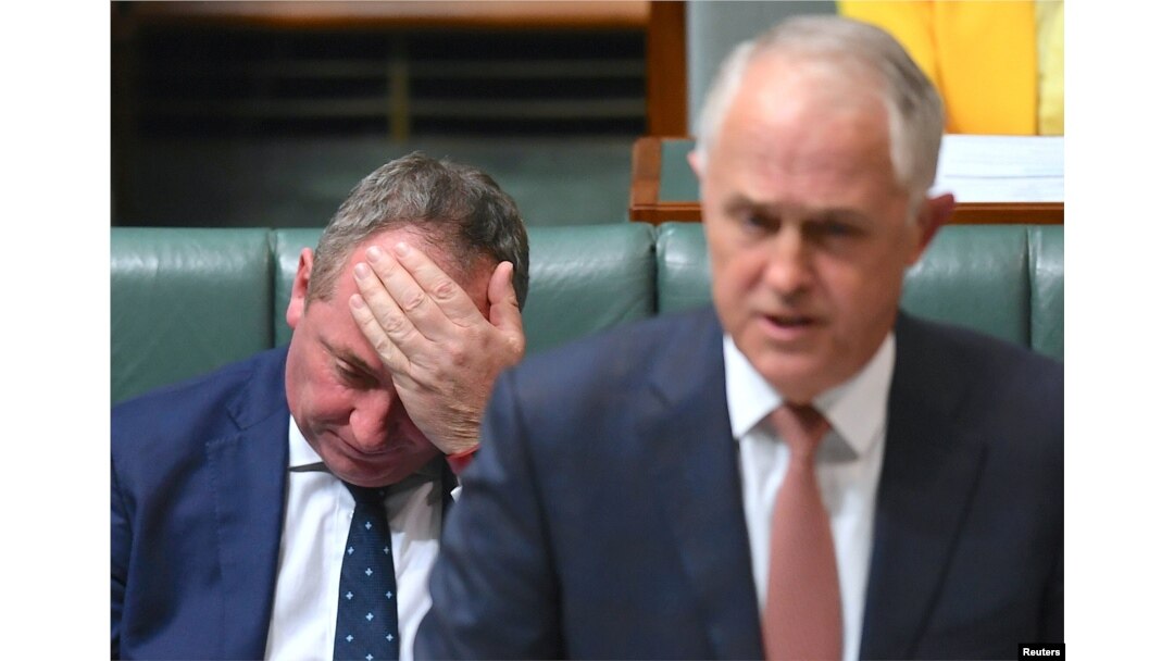 FILE - Australian Deputy Prime Minister Barnaby Joyce reacts as he sits behind Australian Prime Minister Malcolm Turnbull in the House of Representatives at Parliament House in Canberra, Australia, Oct. 24, 2017.