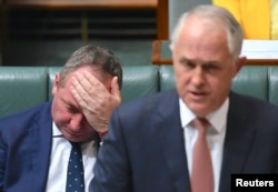 FILE - Australian Deputy Prime Minister Barnaby Joyce reacts as he sits behind Australian Prime Minister Malcolm Turnbull in the House of Representatives at Parliament House in Canberra, Australia, Oct. 24, 2017.