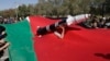 A Houthi supporter carries a mock rocket as he peers from a Palestinian flag during a protest in Sanaa, Yemen, on Jan. 22, 2025.