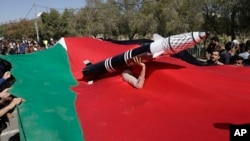 A Houthi supporter carries a mock rocket as he peers from a Palestinian flag during a protest in Sanaa, Yemen, on Jan. 22, 2025.