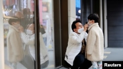 A man and a boy wear masks to prevent contracting a new coronavirus at Myeongdong shopping district in Seoul, South Korea, February 20, 2020. REUTERS/Heo Ran