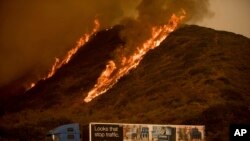 Flames from the Thomas fire burn above a truck on Highway 101 north of Ventura, California, Dec. 6, 2017. 