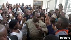 FILE - Freeman Mbowe, center, chairman of Chadema, Tanzania's main opposition party, arrives at Kisutu Magistrate Court in Dar es Salaam, March 10, 2020.