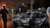 People survey the aftermath of a fiery car crash outside the National Cancer Institute in Cairo, Egypt, Monday, Aug. 5, 2019. 