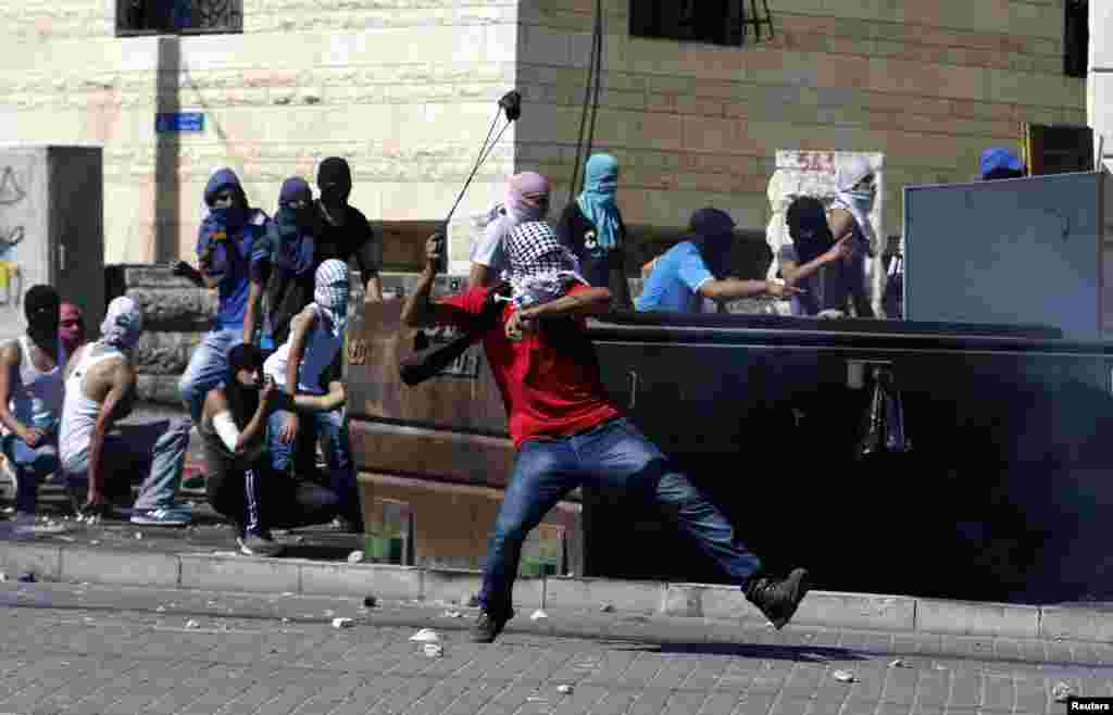 A Palestinian hurls a stone towards Israeli police during clashes in Shuafat, an Arab suburb of Jerusalem, July 2, 2014.
