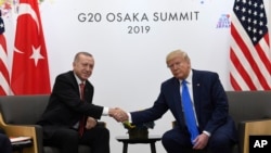 FILE - President Donald Trump, right, shakes hands with Turkish President Recep Tayyip Erdogan during a meeting on the sidelines of the G-20 summit in Osaka, Japan, June 29, 2019. 