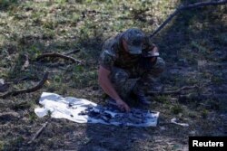 A police officer inspects pieces of a missile found in a crater that appeared during a Russian strike on the Kyiv area of Ukraine, Aug. 6, 2024.