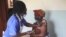 FILE - A nurse administers the AstraZeneca COVID-19 vaccine to a woman at the Butanda Health Centre III in western Uganda, April 27, 2021.