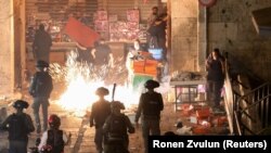 Sejumlah orang Palestina bereaksi saat polisi Israel menembakkan granat kejut dalam bentrokan di Gerbang Damaskus pada malam Laylatulqadar di bulan Ramadan, di Kota Tua Yerusalem, Sabtu, 9 Mei 2021. (Foto: Ronen Zvulun/Reuters)