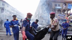 Para petugas penyelamat membawa jenazah korban pemboman mal di Abuja, Nigeria (25/6). (AP/Olamikan Gbemiga)