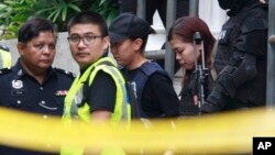 Indonesian suspect Siti Aisyah, second from right, in the ongoing assassination investigation, is escorted by police officers out from Sepang court in Sepang, Malaysia, March 1, 2017. 