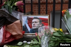 Bunga dan potret mendiang pemimpin oposisi Rusia Alexei Navalny diletakkan di luar Kedutaan Besar Rusia di London, Inggris, 17 Februari 2024. (Foto: Hollie Adams/Reuters)