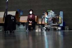 A woman wearing a mask to prevent contracting the coronavirus waits for her flight at Incheon International Airport in Incheon, South Korea, March 19, 2020.