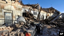 A view of remains of a car covered by debris and buildings damaged in an earthquake in Petrinja, Croatia, Tuesday, Dec. 29, 2020. 