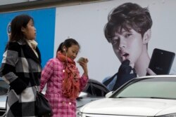 Chinese women walk past advertisement featuring teen idol Lu Han, also known as China's Justin Bieber in Beijing. (AP Photo/Ng Han Guan, File)