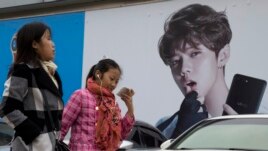 Chinese women walk past advertisement featuring teen idol Lu Han, also known as China's Justin Bieber in Beijing. (AP Photo/Ng Han Guan, File)