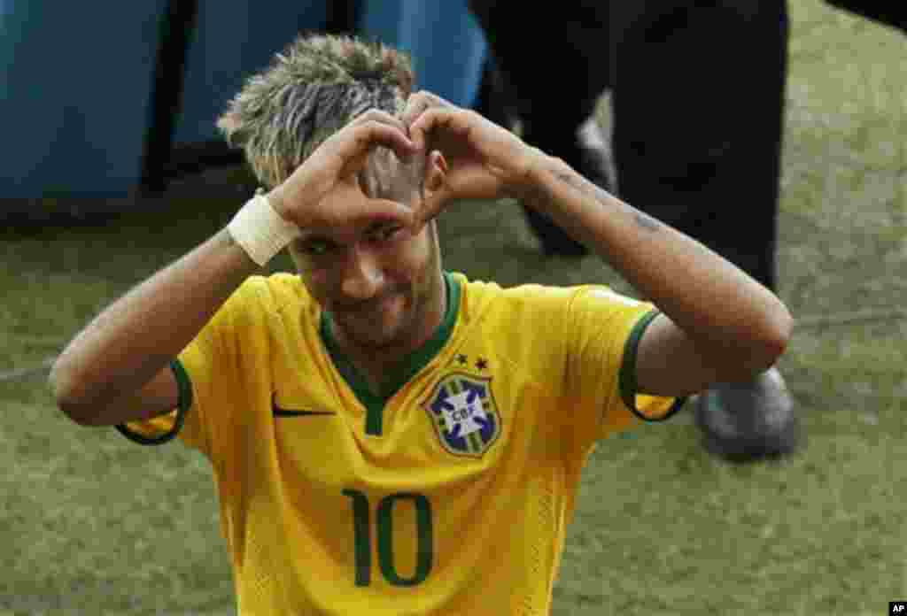 Brazil's Neymar forms a heart with his hands as he leaves the pitch after the World Cup round of 16 soccer match between Brazil and Chile at the Mineirao Stadium in Belo Horizonte, Brazil, Saturday, June 28, 2014. Brazil won 3-2 on penalties after the mat